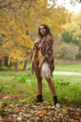 Happy Portrait fashion of a beautiful young Caucasian woman with a scarf,long legs  and yellow pullover in autumn park,red green yellow threes. Autumn, season and people concept.Autumn lifestyle