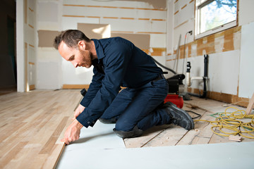 A Male Worker install wood floor on a house