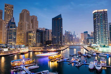 Fototapeta na wymiar Dubai marina with boats and buildings with gates at night