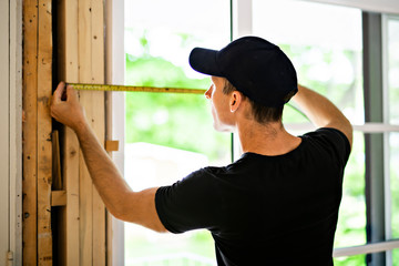 A handsome young man installing Double Sliding Patio Door in a new house construction site