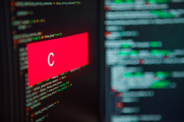 Programming language, C inscription on the background of computer code.