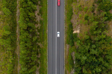 Aerial view from above of a country road through a green forest