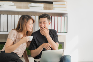 Romantic young Asian couple in happy mood using tablet while his girlfriend drink coffee in modern room, Eye contact each other