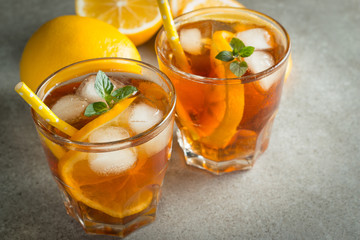 Glasses of cold ice tea with lemon, ice, mint on background. Homemade lemonade. Spring and summer drinks and beverages concept.