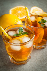 Glasses of cold ice tea with lemon, ice, mint on background. Homemade lemonade. Spring and summer drinks and beverages concept.