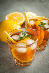 Glasses of cold ice tea with lemon, ice, mint on background. Homemade lemonade. Spring and summer drinks and beverages concept.