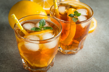 Glasses of cold ice tea with lemon, ice, mint on background. Homemade lemonade. Spring and summer drinks and beverages concept.