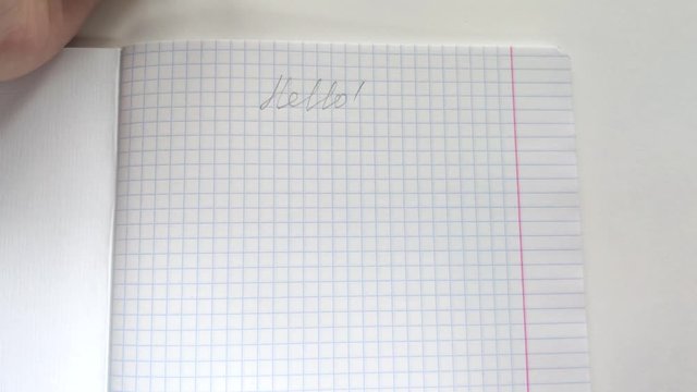 White european woman lefty writes in pencil in a notebook with his left hand the phrase Hello!