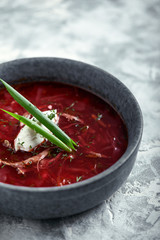 Traditional Ukrainian Russian borsch with sour cream on a bowl. A plate of red beetroot soup borsch on a gray marble background. Traditional Ukrainian cuisine