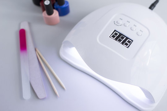 Gel uv led nail white lamp, gel polish, nail files, accessories for manicure. Modern beauty treatments for a beauty salon or at home procedures on a light gray background. Top-view