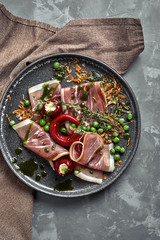 Italian prosciutto crudo and jamon with rosemary. Raw ham on a concrete gray background.