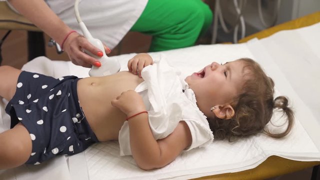 A top view of a pediatrician performing ultrasound abdomen examination in hospital. Medical procedure. Healthcare concept