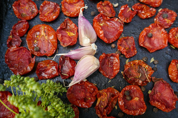 Tomatoes dried on baking tray. Preparation dried tomatoes with garlic