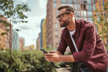 Good news. Side view of handsome man with stubble in casual clothes and eyeglasses leaning at his...