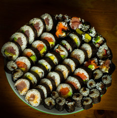  A large plate full of colorful futomaki sushi and hosomaki on a white plate on a wooden background