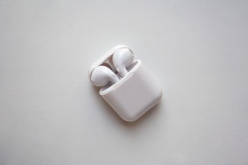 Wireless ear buds in glossy white plastic case isolated on white background