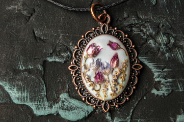 Flowers in epoxy. Pendant on a dark background.