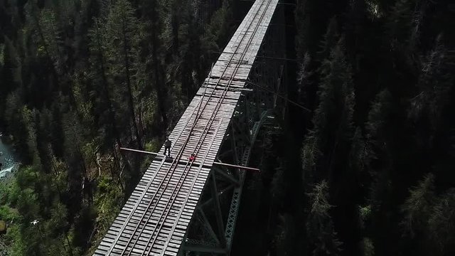 Thrill Seeker Standing on Abandoned Vance Creek Railroad Bridge Over Deep Canyon in Washington State, USA, Orbit Aerial