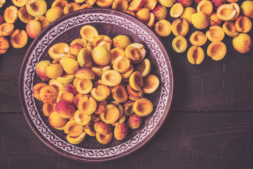 halves of apricots in a ceramic plate on a wooden background top view. apricots and copy space. halves of apricots lay flat.