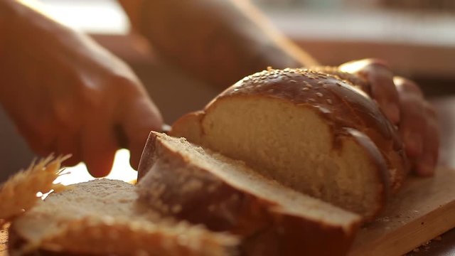 A man cutting fresh crisp bread or roll, close-up