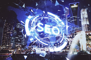 SEO hologram on city view with skyscrapers background double exposure. Search optimization concept.