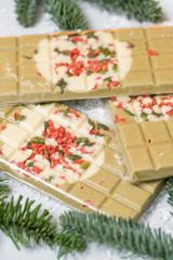 Obraz na płótnie Canvas Handmade chocolates bar. Christmas theme. White chocolate bar with pistachio nuts and dried fruit cherries. . Copy space