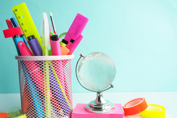 glass globe on pink stickers and bright stationery in stand and on a white table...