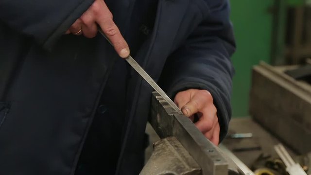 Locksmith files a large part in a vise. File processing, close-up. File unevenness. Locksmith in the shop at work.
