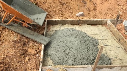 Worker pouring the mixed cement onto the ground for making the foundation of structure