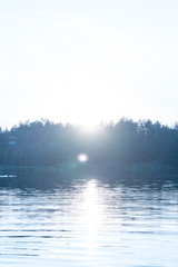 View of the water in the quarry, on the silhouette of the forest on the opposite bank. Summer sunset. Vertical