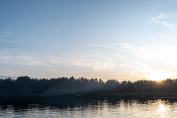 Fototapeta premium Picturesque landscape. View to a quarry filled with water, to a forest on the opposite bank on a summer evening at sunset. 