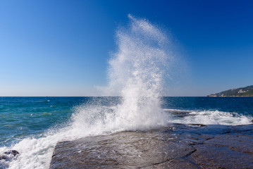 waves of high altitude break on the big stones of the embankment in the city of Yalta, on a bright sunny day.