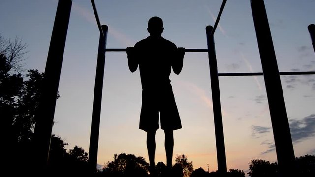Young Male Silhouette Exercising Pullups Before Sunrise