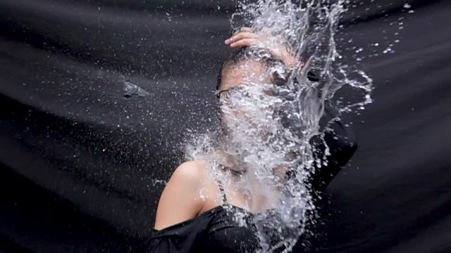 An attractive female model is hit by a large water balloon that explodes in slow motion