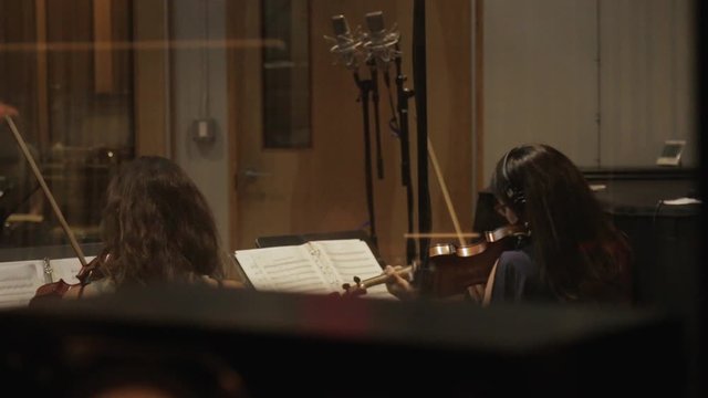 Sliding Shot of Orchestra Playing Instruments in Recording Studio