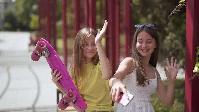 Two young girls sitting in a park, enjoying music from a smartphone