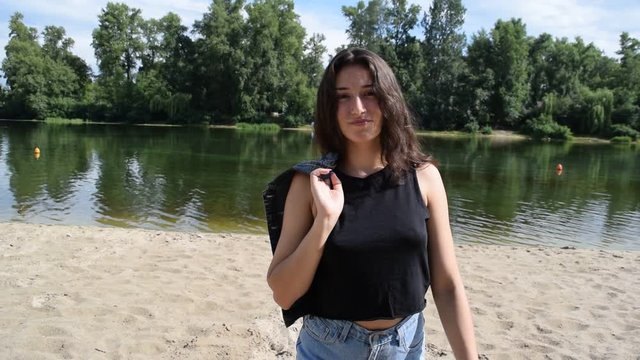 Young brunette girl in black tank top near the water in the river.