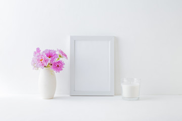 Mockup with a white frame and pink flowers in a vase on a white table
