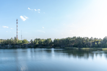 Scenic view from the top of the quarry to the blue water and the opposite shore and forest on a summer sunny day. 