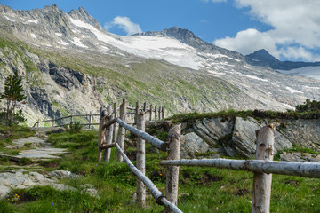 Fototapeta na wymiar Holzzaun am Wanderweg mit Gletscher im HIntergrund
