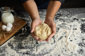 male hands hold raw dough on a wooden background. Milk and Raw Chicken Eggs