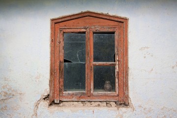 old and destroyed window with wooden frame and broken glass, detail of a deserted desolate country house, spirits of past life symbol