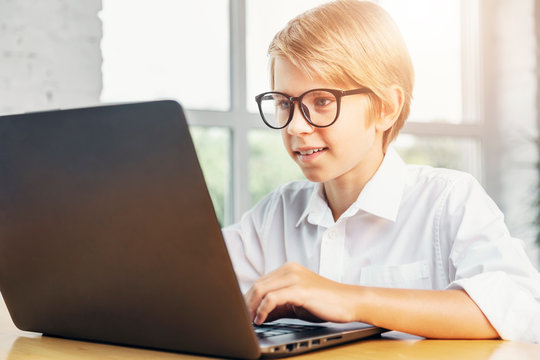 Concentrated kid in glasses using laptop