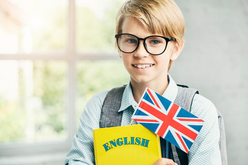 Smiling blond pupil with textbooks and british banner