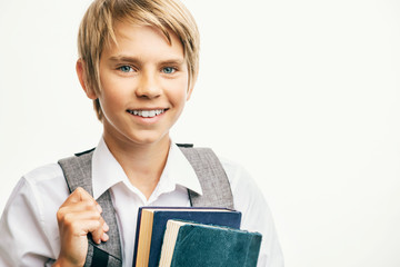 Smiling blond boy carrying books and a schoolbag