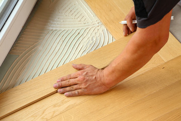 Fototapeta na wymiar Worker laying parquet flooring. Worker installing wooden laminate flooring