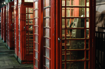 Row of red telephone boxes at night