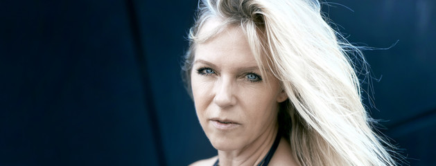 Attraktive reife Frau mit blonden Haaren und strahlenden blauen Augen