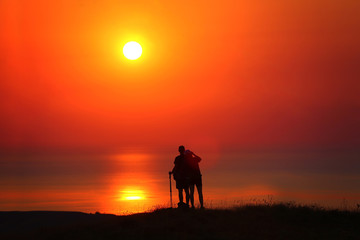 Fototapeta na wymiar Silhouettes of a guy and a girl at sunrise by the sea photograph