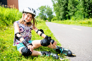 Child on inline skates. Little girl skating on sunny summer day.